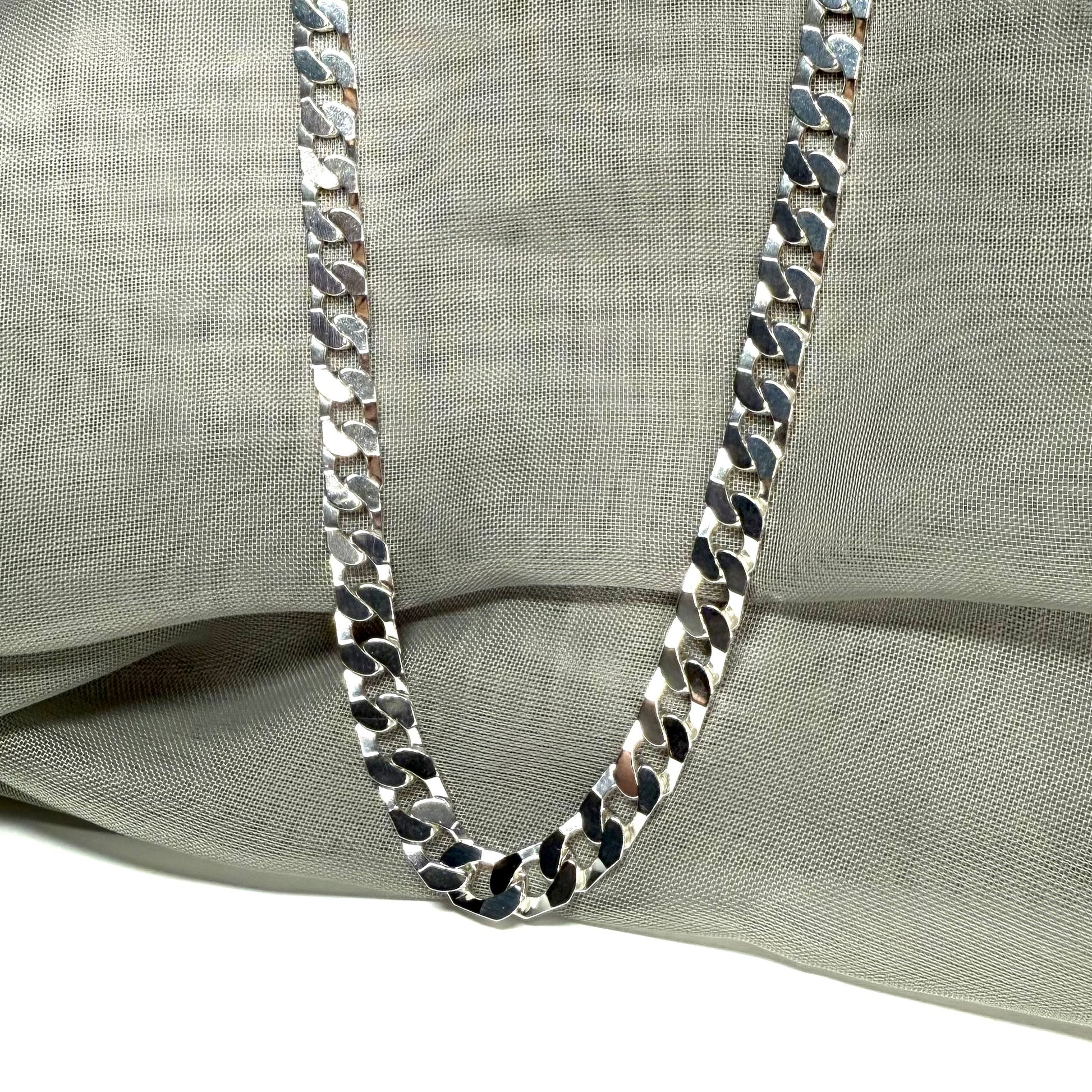 Silver chain necklace on a light gray fabric background