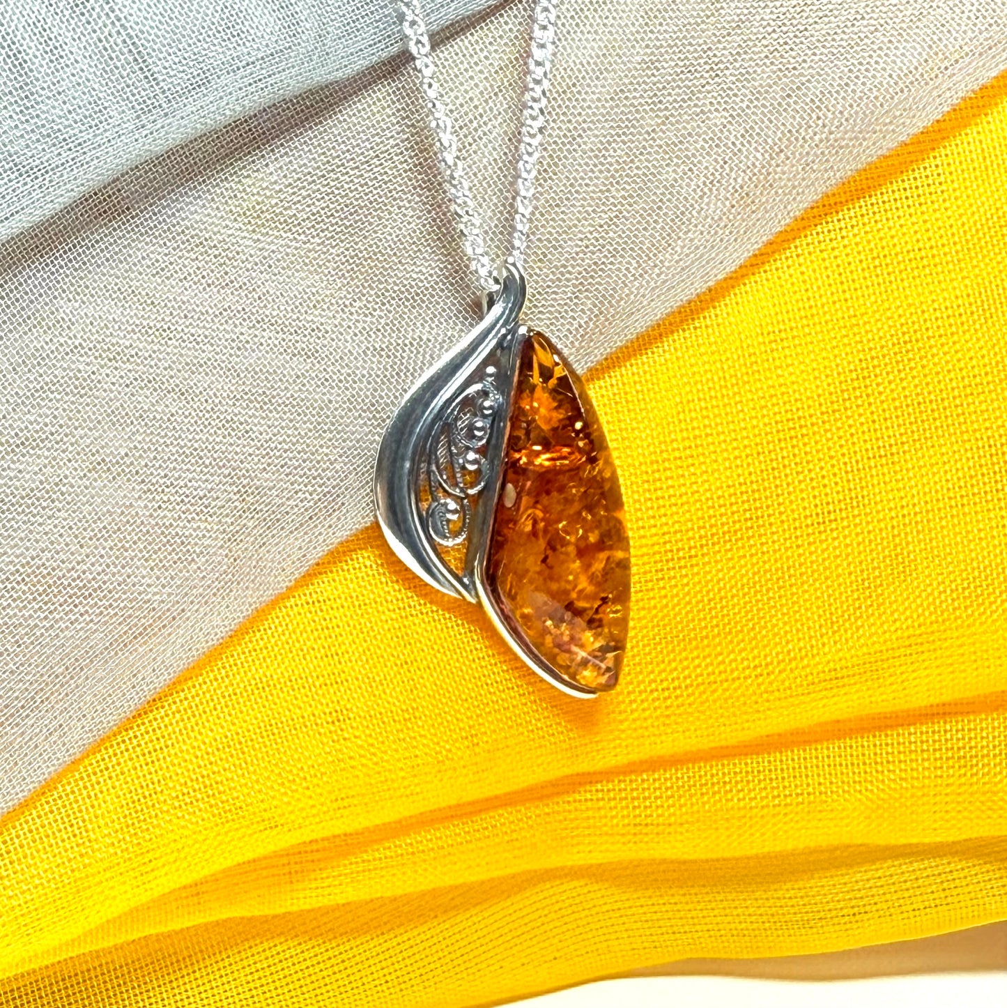 A Sterling silver real amber irregular marquise shaped necklace swirled open pendant