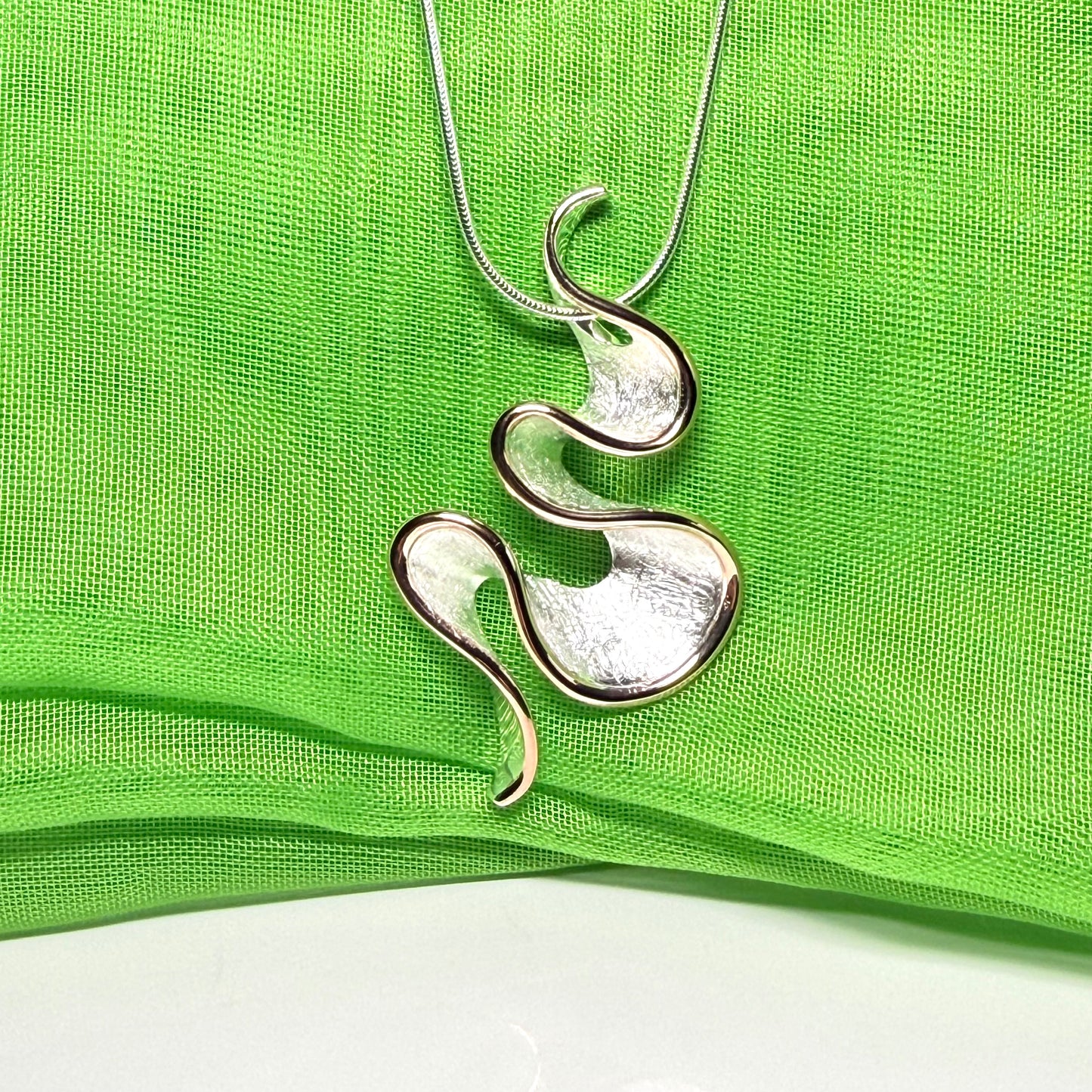 A sterling silver solid rounded open pierced fancy swirl necklace with snake chain