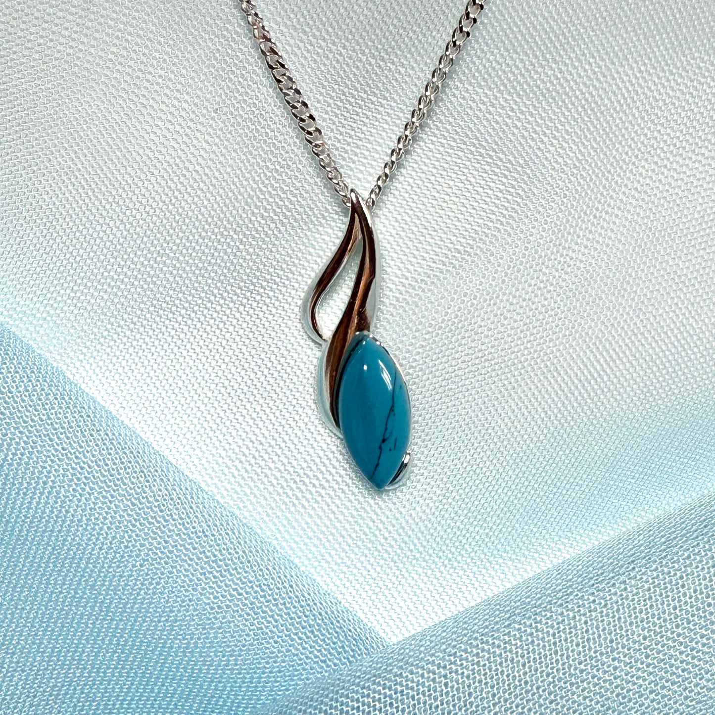 Necklace with a blue pendant on a light blue fabric background