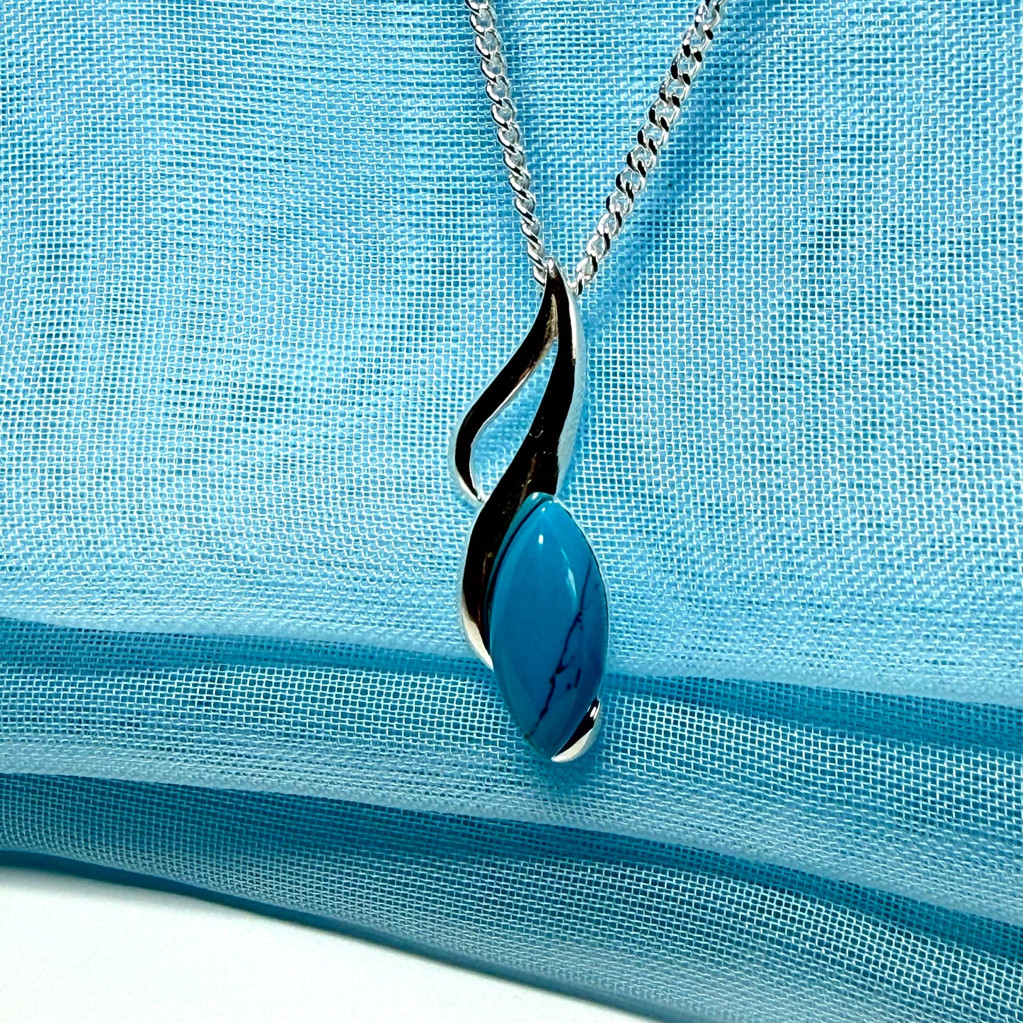 Necklace with a blue pendant on a light blue fabric background