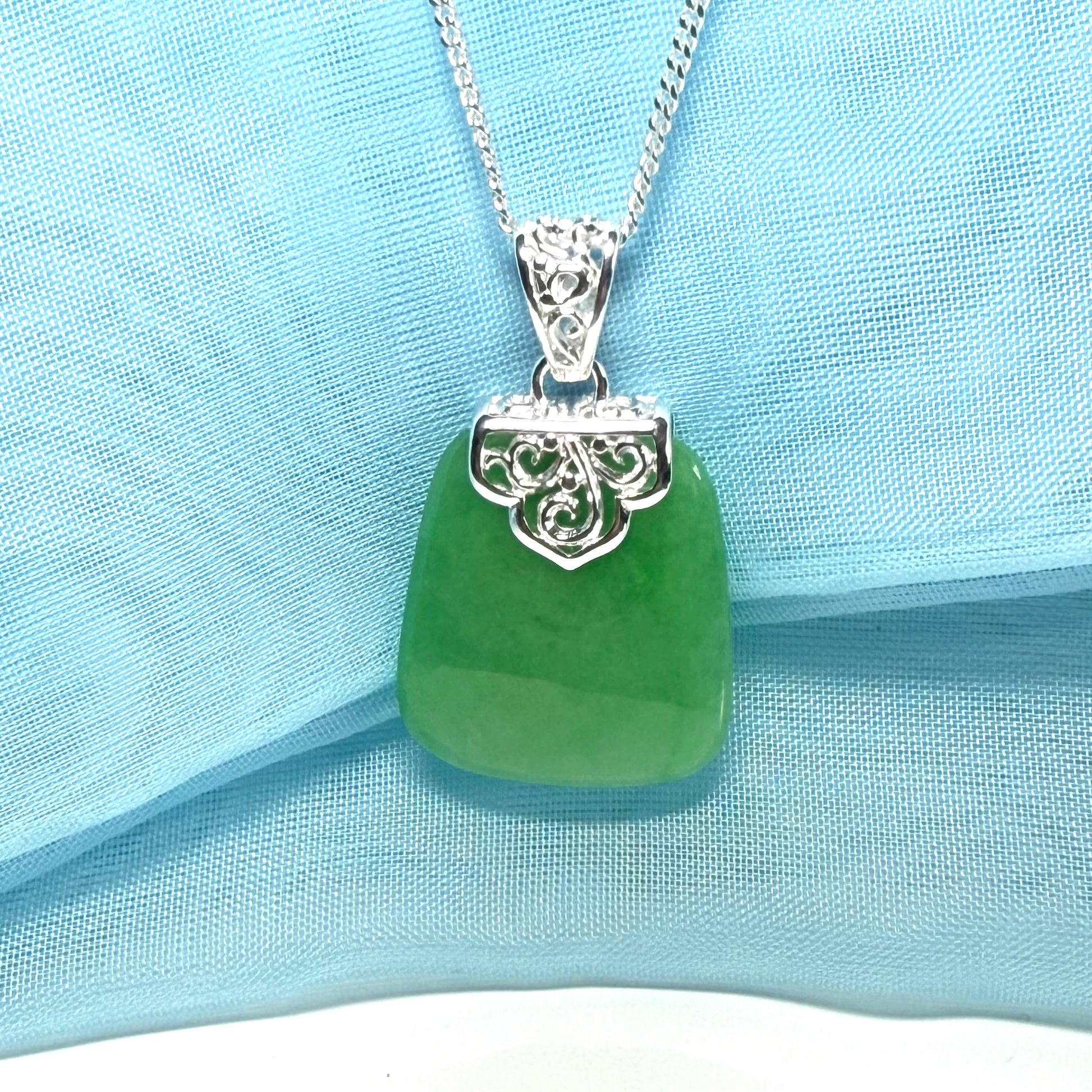 Green pendant necklace on a light blue fabric background