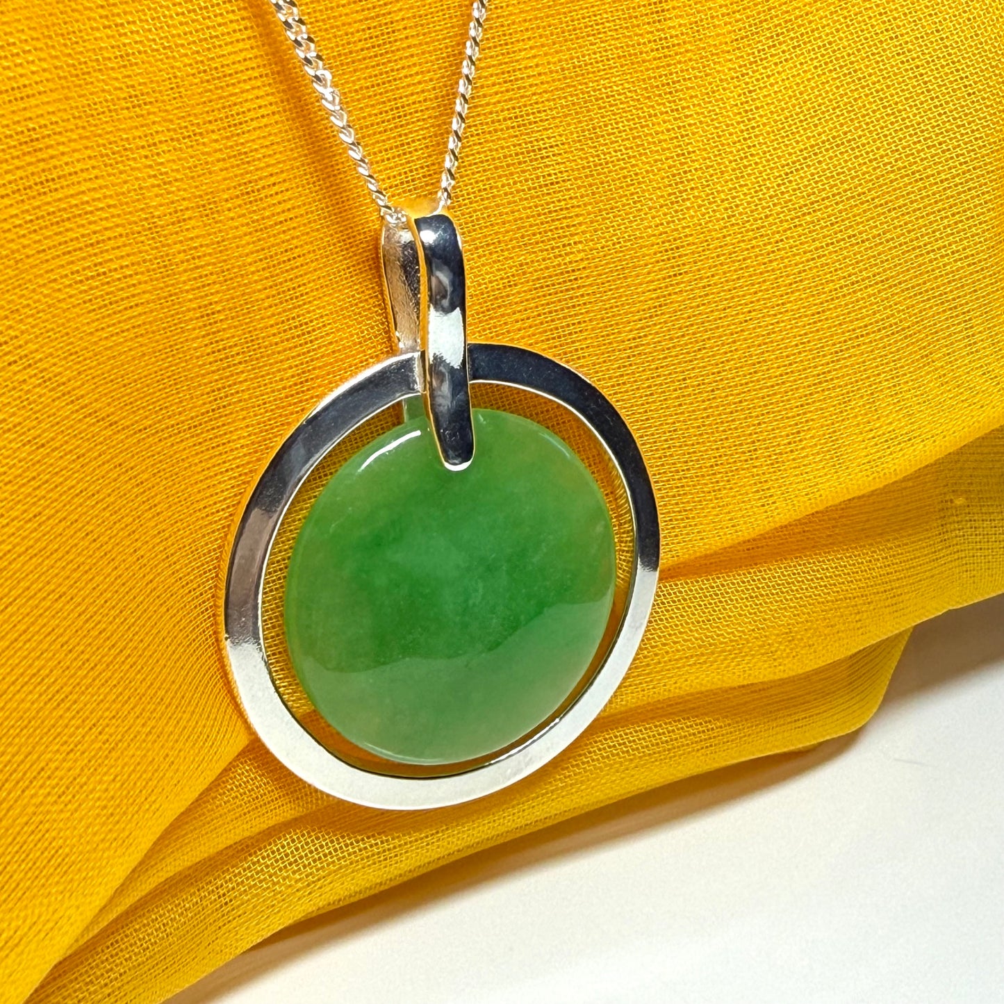 A stunning, shimmering large round halo necklace sterling silver circle shaped green real jade