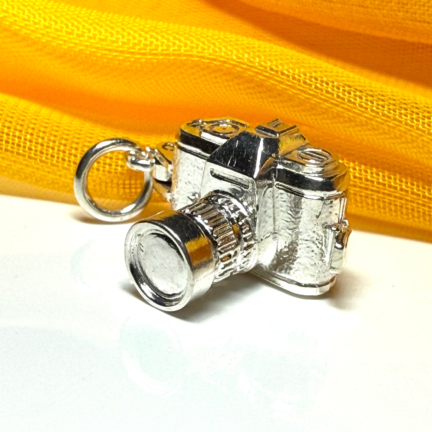 Camera charm

Solid

Sterling silver

This beautiful sterling silver traditional lens camera shaped charm, is a perfect addition to a silver charm bracelet collection.

Alternatively it would look great worn around the neck on a silver chain together with other treasured pieces or simply on its own.

The charm is a classic zoom lens camera ideal for the photography enthusiast but it also has a hinge and when it is opened it reveals a picture of a couple inside the back cover section.

It could be given as a