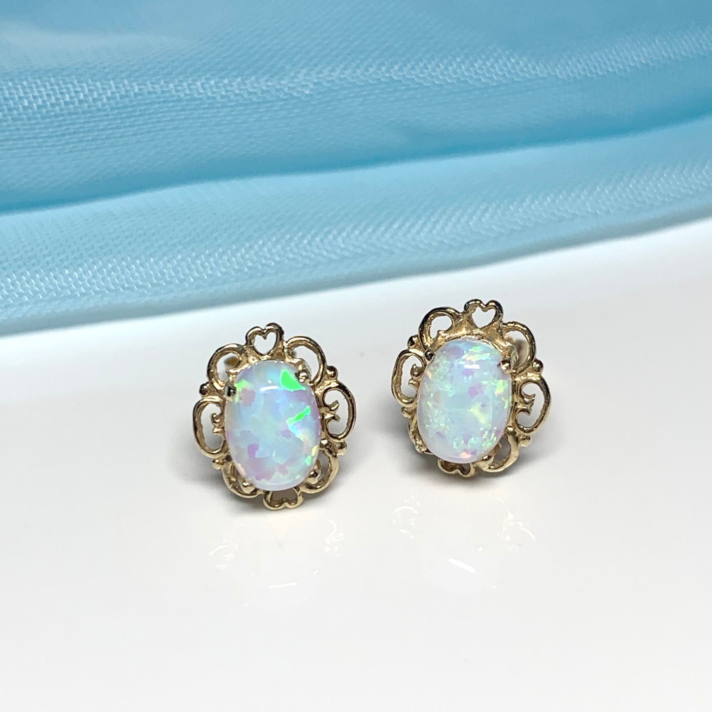 Yellow gold oval opal stud earrings with a pierced setting