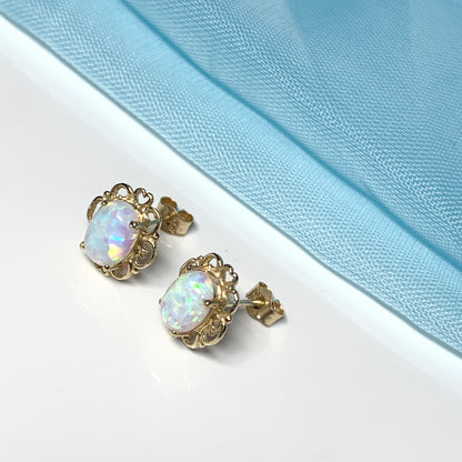 Yellow gold oval opal stud earrings with a pierced setting