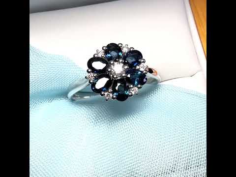 A video of a white gold real dark blue sparkling sapphire and diamond round shaped cluster ring