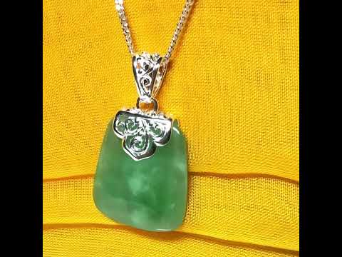 A real green jade necklace large shaped with a patterned top pendant with chain