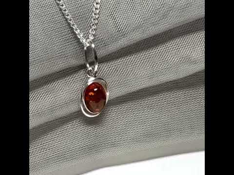 Orange real amber oval sterling silver necklace with a swirl set open pierced pendant