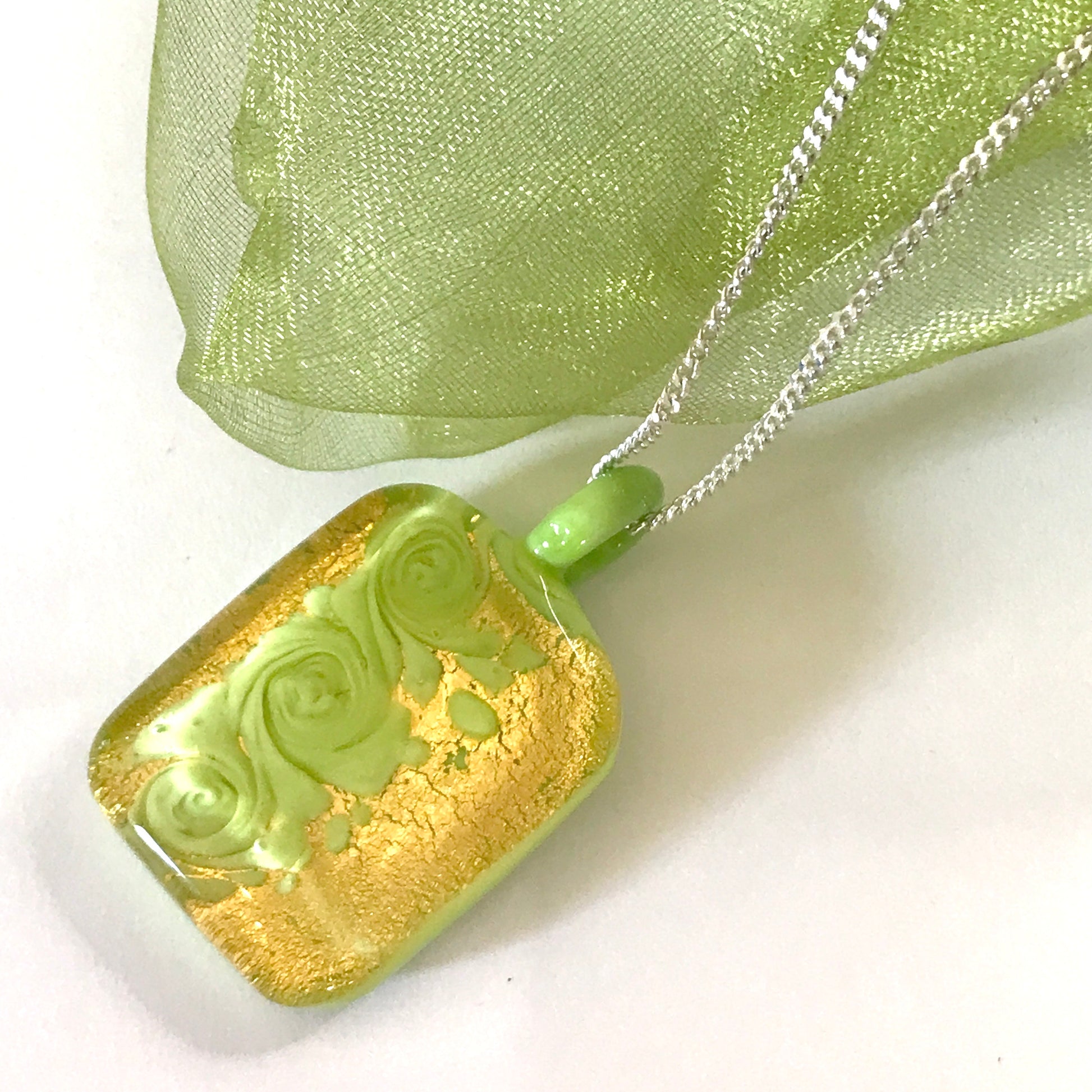 Necklace with a green and gold pendant on a white background